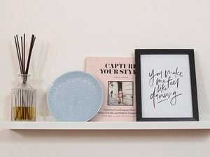 Wall-mounted shelf with a book, plate, vase and photo frame