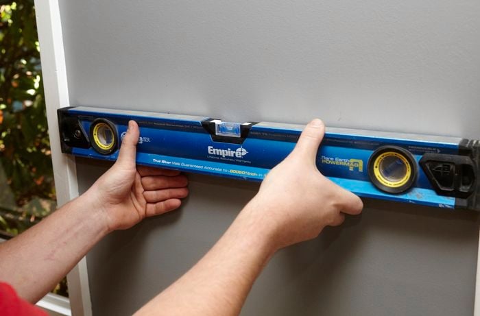  A person placing spirit level on a wall next to a window
