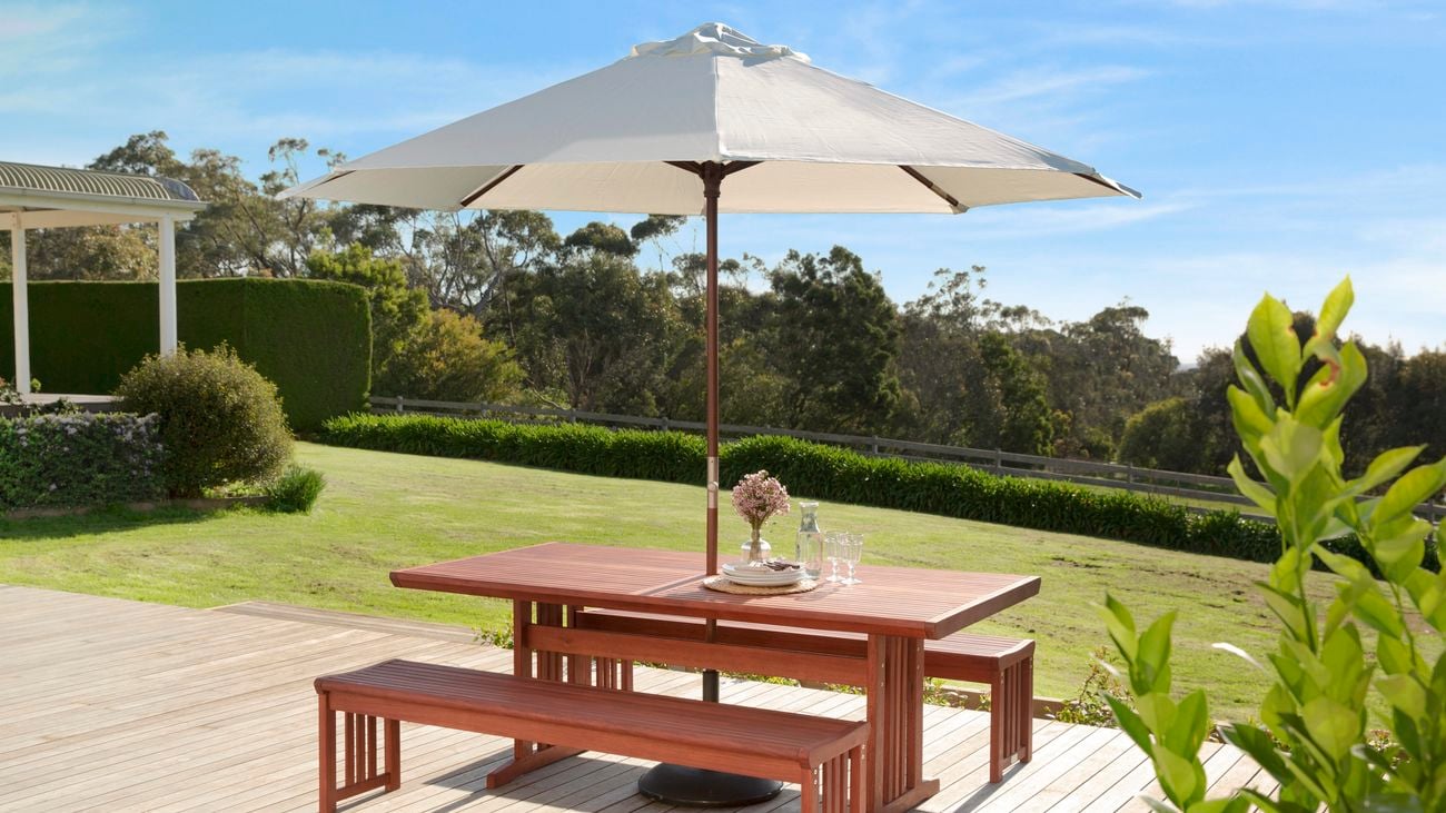Outdoor table and bench seats covered by a large umbrella.