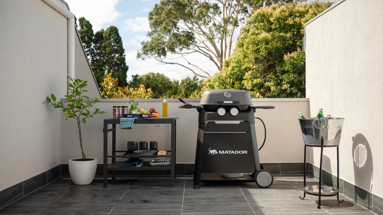 Outdoor balcony area with a barbecue machine and a table next to it.