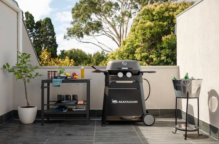 Outdoor balcony area with a barbecue machine and a table next to it.