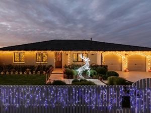 Modern house decorated with Christmas lights with a light up reindeer in the front yard.