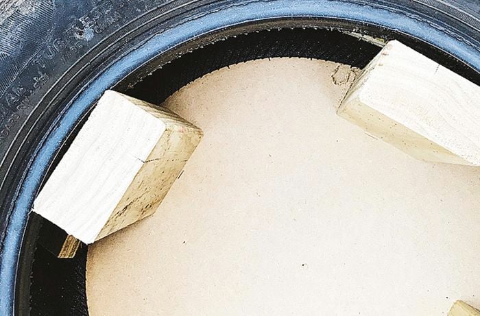 A positioned four pieces of framing timber evenly inside a tyre.