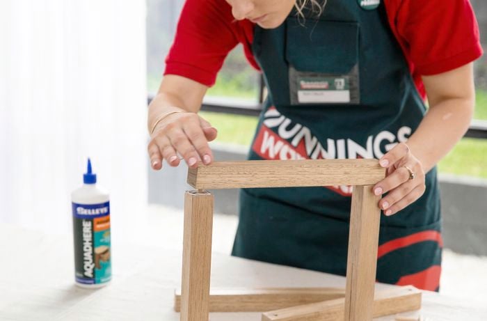 Two parts of a wooden plant stand being joined together with dowel