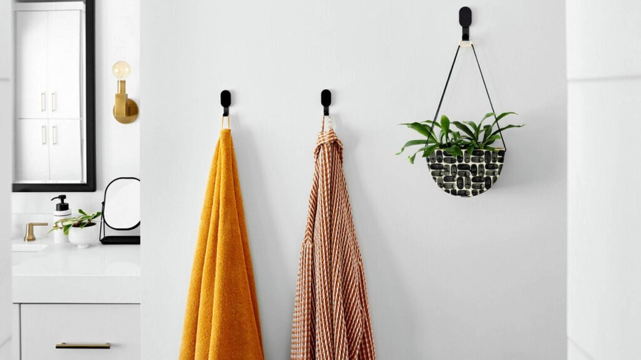 bathroom with white walls and black 3M hooks holding up bath towels