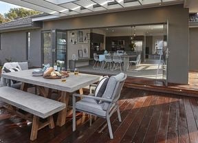 A completed backyard deck attached to a grey painted house