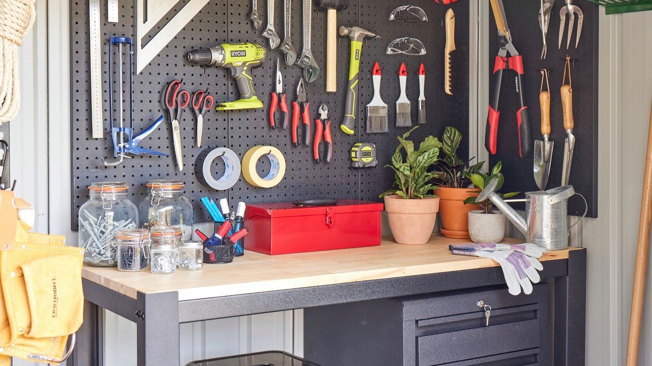 Tools hanging onto a black pegboard next to a wooden desk