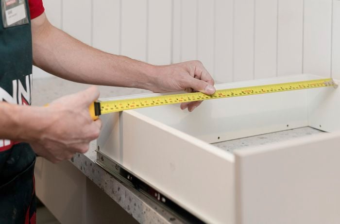 Measuring drawers with a tape measure.