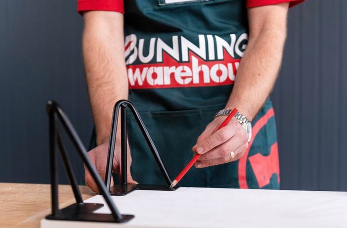 Bunnings team member marking out where the screws will go with a pencil on the timber board