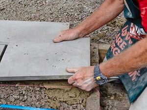 A Bunnings team member laying down a paver onto a layer of grout.