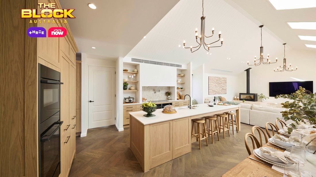 Kitchen with wooden island, open shelving, and dining table set for guests.