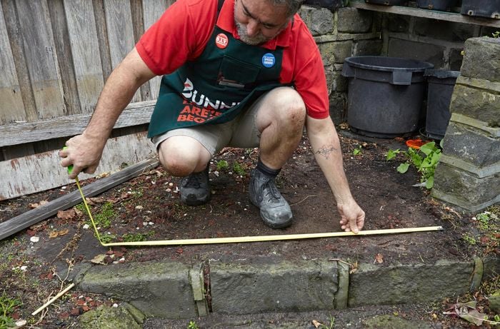 A Bunnings team member measuring the width of a pathway