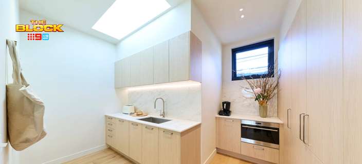 Modern butler’s pantry featuring light timber cabinetry, stone benchtops, integrated appliances and a large skylight.