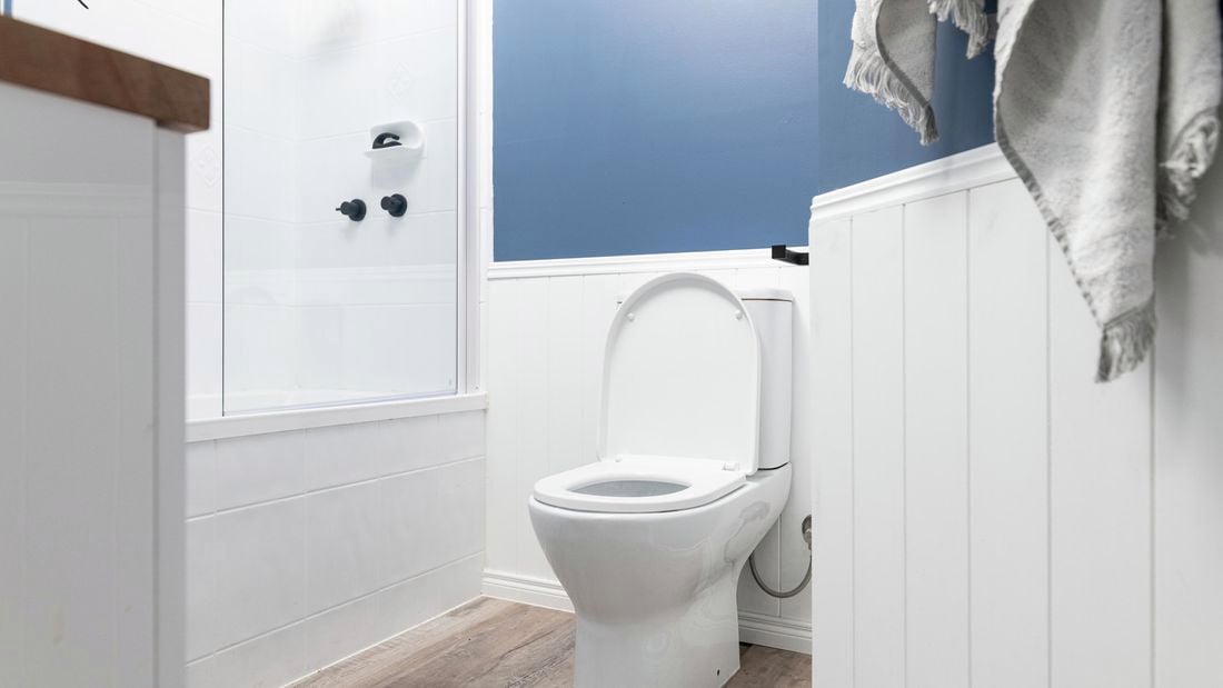 A cleaned toilet in a rustic white and blue themed bathroom