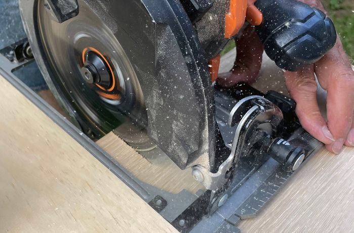 A piece of plywood is being cut with a circular saw