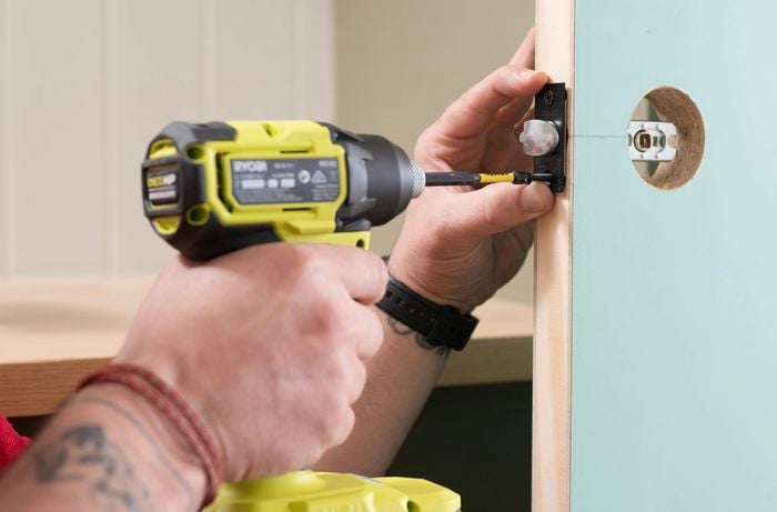 Install the latch mechanism on a green door with a drill