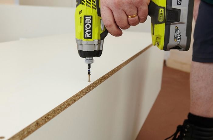 Person drilling screw into panel of pantry