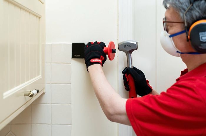 Person using chisel and hammer to remove first wall tile