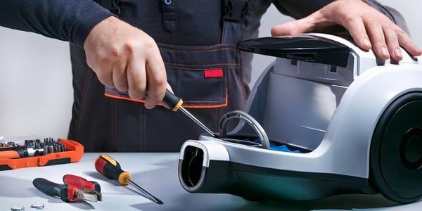 A person repairing a vacuum.