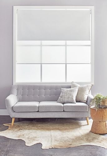 Interior of a living room with pale grey walls and double roller blinds on the window