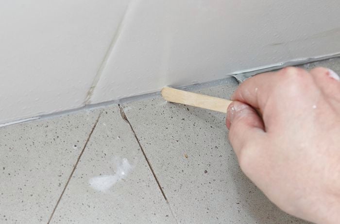 Excess sealant being scraped clear with an icy pole stick