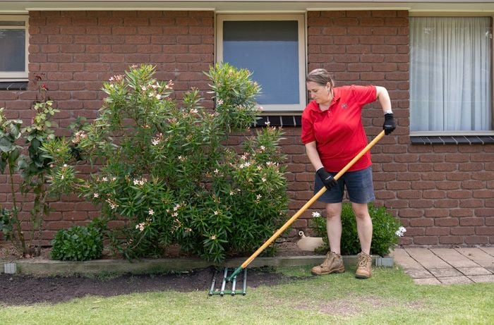 A Bunnings team member is holding a soil spreader. 