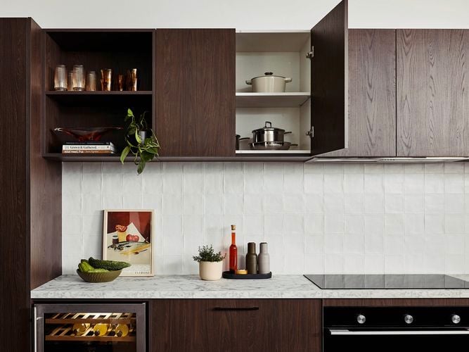 Brown modern kitchen with Marble benchtops with crockery on it and an oven in it.