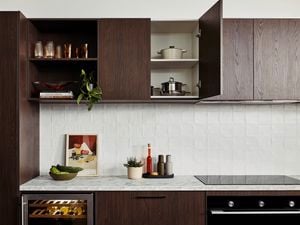 Brown modern kitchen with Marble benchtops with crockery on it and an oven in it.