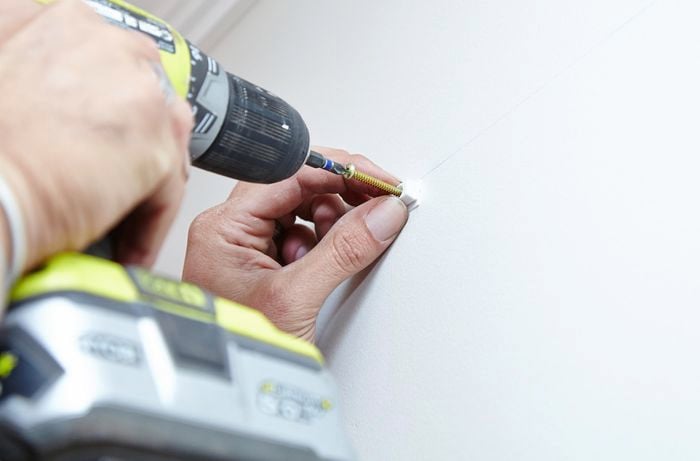 Brackets being screwed into the wall plugs