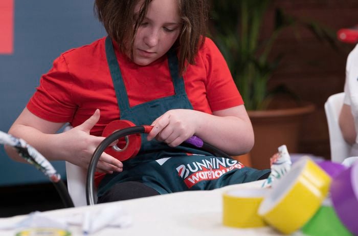 A girl is decorating a hula hoop with red tape.