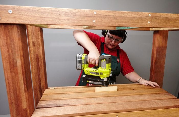 Person drilling slats to create bottom shelf of DIY kitchen island table.