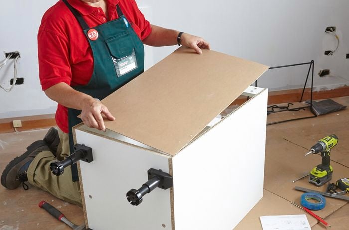 Person attaching back piece to linen chute cupboard.