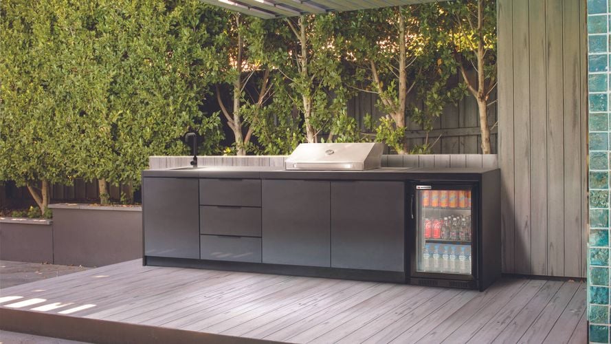 Alfressco BBQ kitchen displaying small drink fridge and mature garden