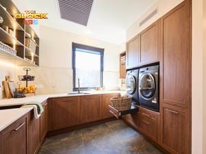 Laundry room from The Block with timber cabinetry, stacked washer and dryer, large sink, and open shelving.