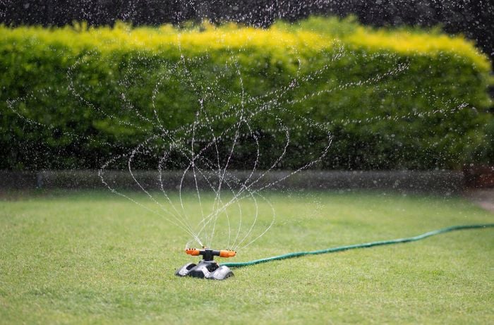 An image showing a lawn with a lawn sprinkler watering the grass.