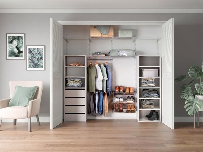 A wardrobe in a room with a chair and a pot plant in it