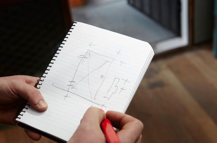 Person drawing up measurements in a notebook.