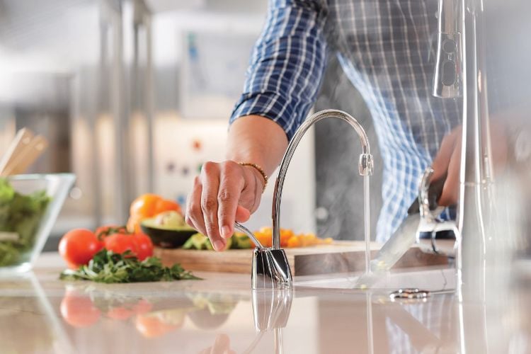 Person cleaning kitchen knife with hot filtered water dispenser