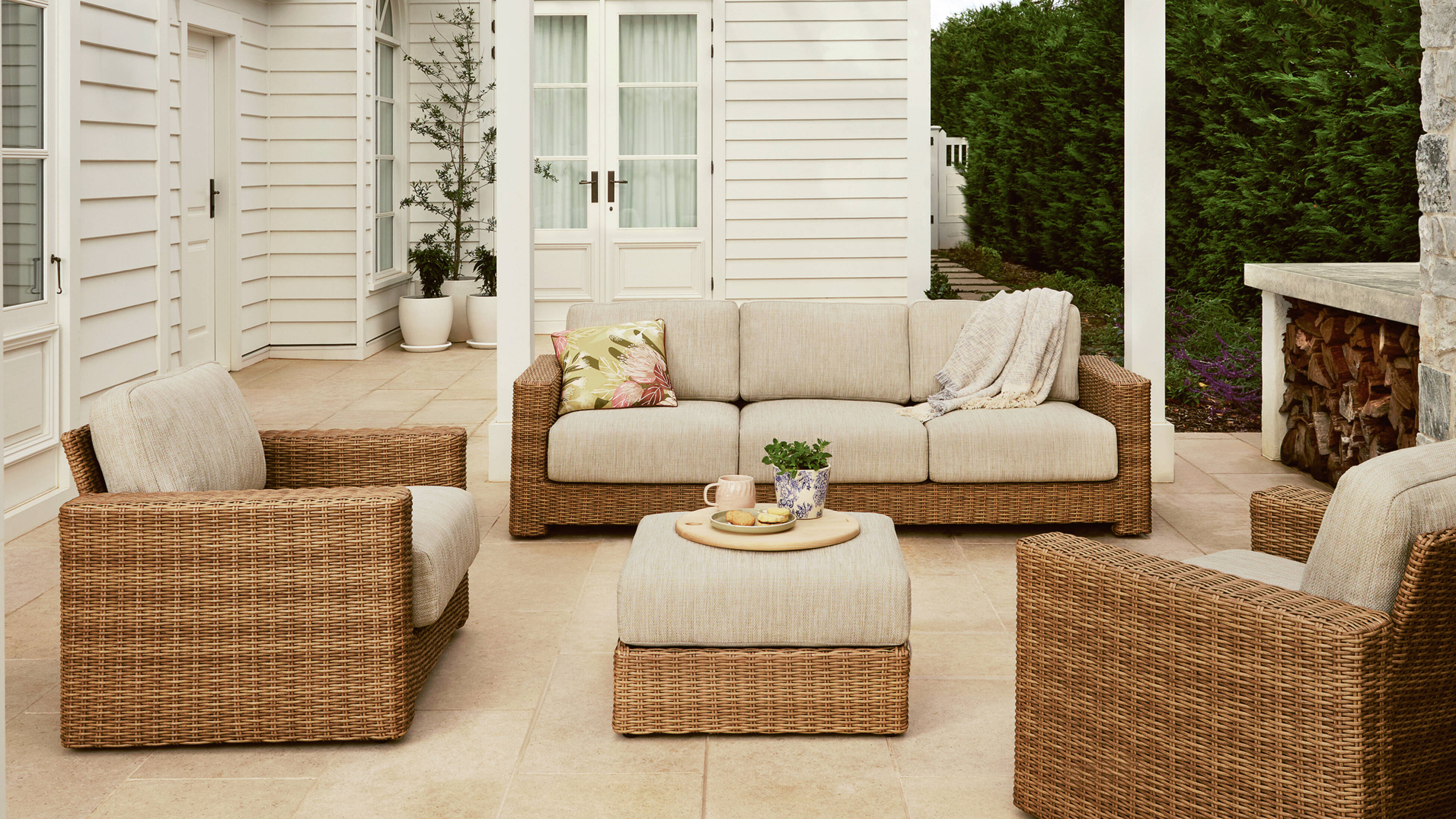 Outdoor patio with wicker sofa, chairs, ottoman, and pet bed.