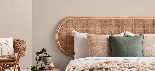 Bedroom with beige walls, a bed, a side table and a chair in it.