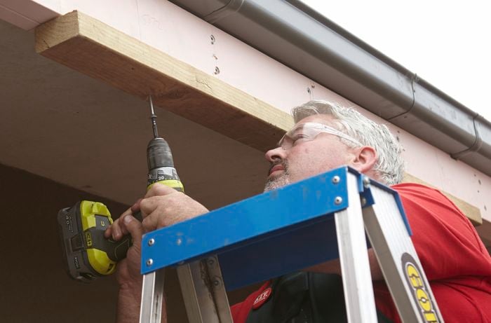 Person drilling extra piece of timber in pergola frame.