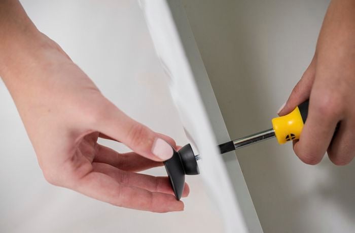 Knobs being attached to a vanity using a screwdriver