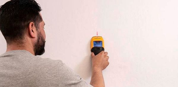 Zircon branded stud finder being used by a Man to find stud