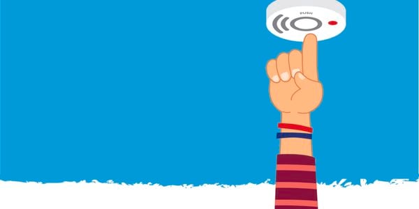 Illustration of a hand reaching up and pressing the test button on a ceiling-mounted smoke alarm, with sound waves and a red indicator light visible against a blue background.