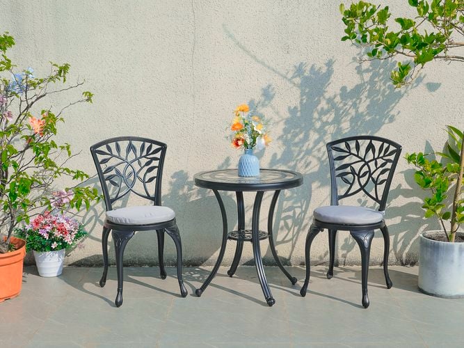 A cast aluminium outdoor dining setting with two armless chairs and a table