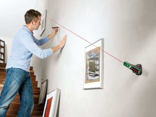 Man marking levels for hanging pictures along staircase