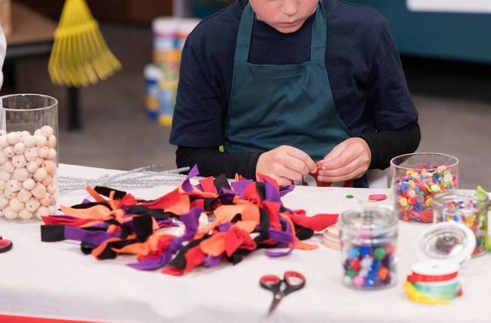 A young boy is creating a loop with a button for hanging