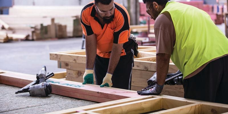 Two Bunnings team members assembling a building frame with nail guns