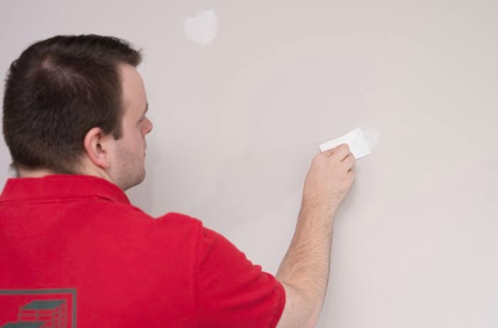  A Bunnings Team Member is using a putty knife to fill the cracks in the wall to ensure the paint and adhesive will stick properly.
