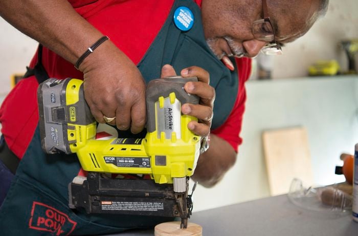A person attaching a plywood circle to a piece of dowel using a cordless driver